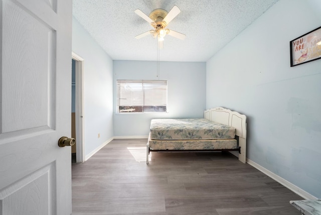 bedroom with a textured ceiling, wood finished floors, a ceiling fan, and baseboards