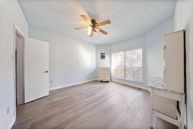 unfurnished room featuring a textured ceiling, wood finished floors, and baseboards