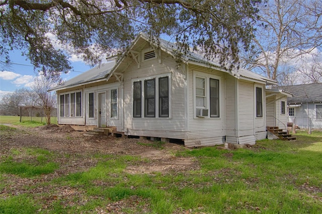 back of property featuring entry steps, metal roof, and a yard