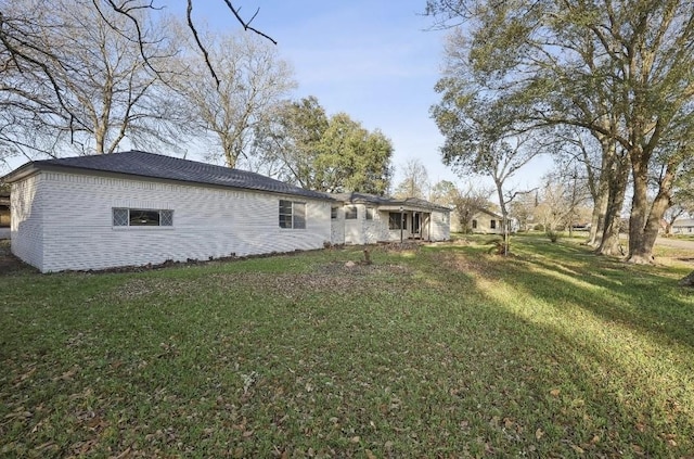 back of property featuring brick siding and a lawn