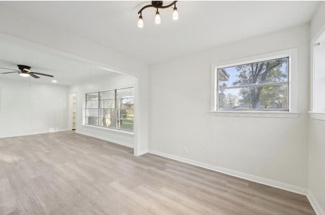 spare room featuring ceiling fan, baseboards, a wealth of natural light, and wood finished floors