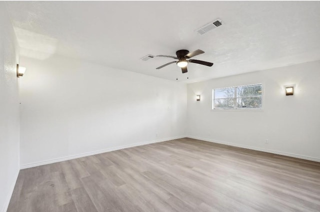 spare room with baseboards, visible vents, ceiling fan, and wood finished floors