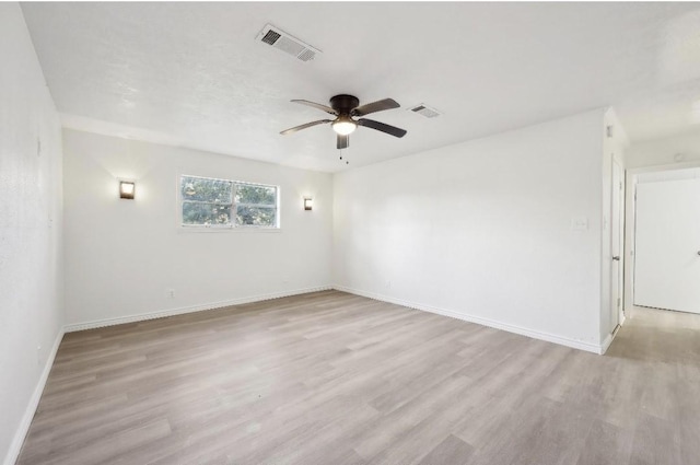 spare room with ceiling fan, light wood-type flooring, visible vents, and baseboards