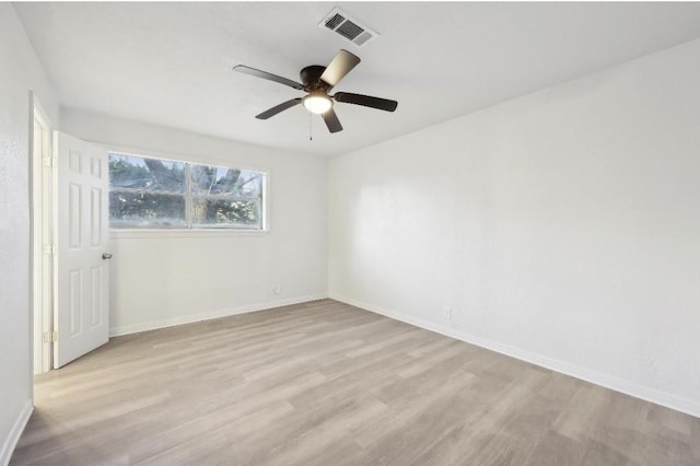 empty room featuring light wood-style flooring, visible vents, and baseboards