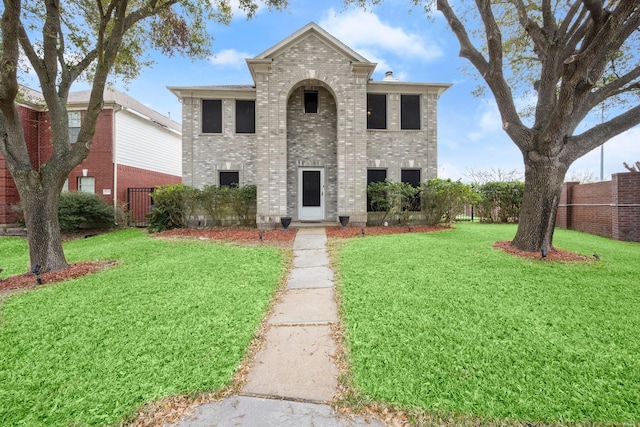 traditional-style house featuring a front lawn, fence, and brick siding