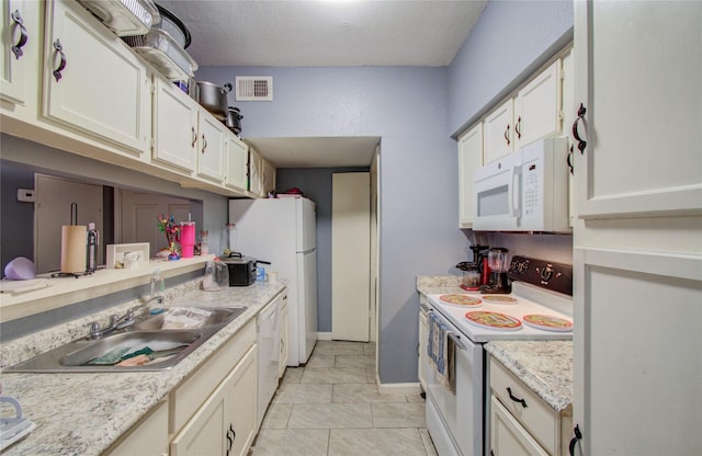 kitchen with light countertops, visible vents, a sink, a textured ceiling, and white appliances