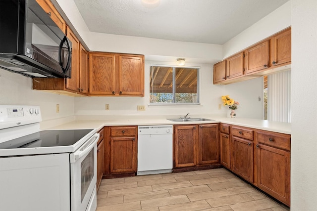 kitchen with wood finish floors, light countertops, brown cabinetry, a sink, and white appliances