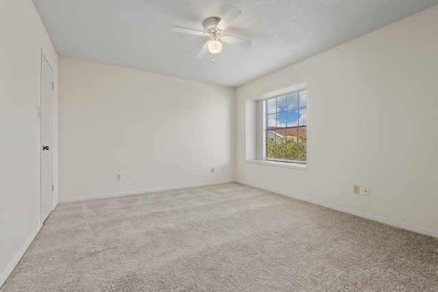 empty room featuring a textured ceiling, baseboards, a ceiling fan, and light colored carpet