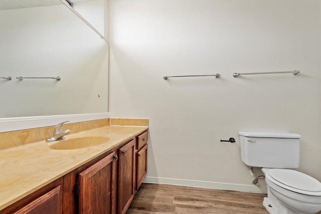 bathroom featuring toilet, baseboards, wood finished floors, and vanity