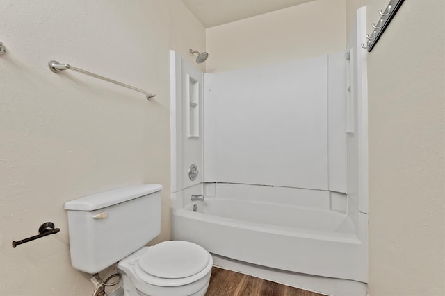 bathroom featuring toilet, wood finished floors, and washtub / shower combination