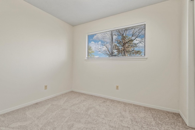 empty room featuring baseboards and light colored carpet