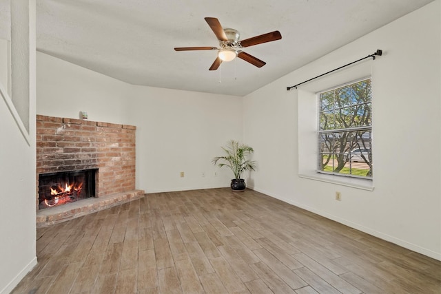 unfurnished living room featuring a fireplace, wood finished floors, a ceiling fan, and baseboards