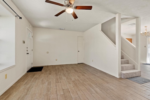 unfurnished living room with visible vents, stairway, and wood finished floors