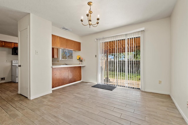 kitchen with white range with electric stovetop, visible vents, an inviting chandelier, brown cabinetry, and light wood-style floors