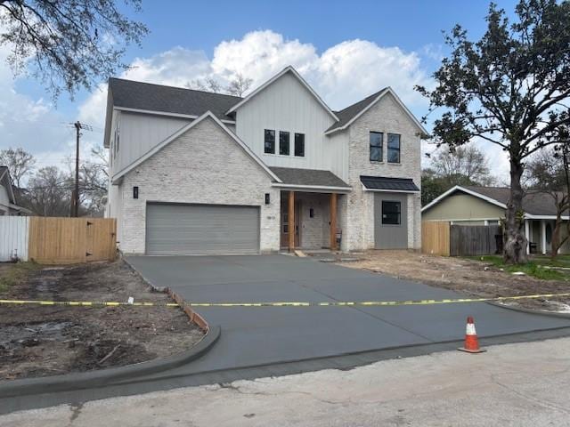 traditional-style house with a garage, stone siding, driveway, and fence