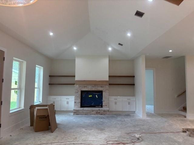 unfurnished living room with lofted ceiling, visible vents, a fireplace, and stairway