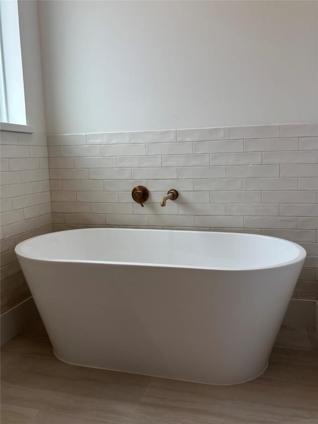 full bathroom featuring a soaking tub and tile walls