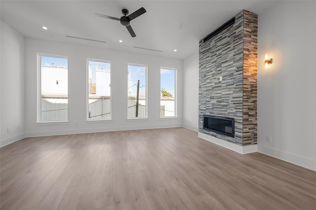 unfurnished living room featuring a ceiling fan, a fireplace, light wood-style flooring, and baseboards