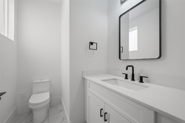 bathroom with marble finish floor, baseboards, vanity, and toilet