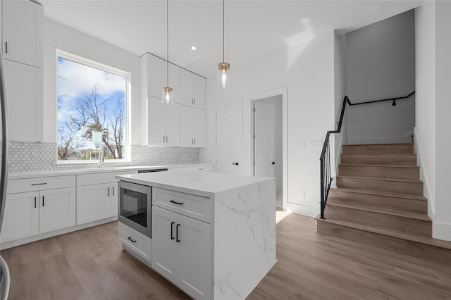 kitchen with light wood-style flooring, built in microwave, and decorative backsplash