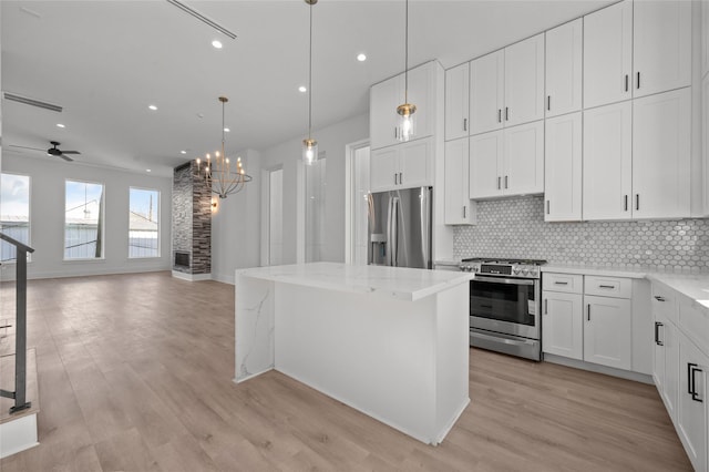 kitchen with appliances with stainless steel finishes, a center island, light wood-type flooring, and tasteful backsplash