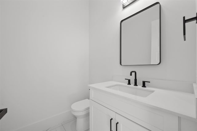 half bathroom featuring toilet, baseboards, and vanity