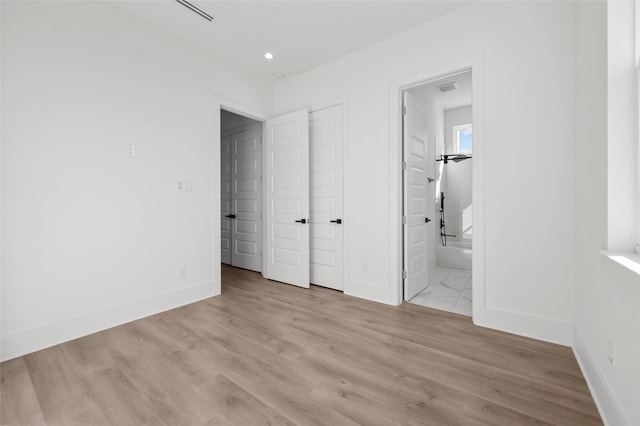 unfurnished bedroom with visible vents, light wood-style flooring, and baseboards