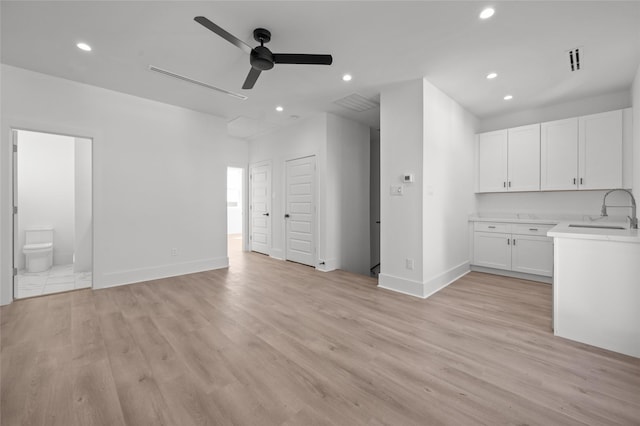 unfurnished living room with recessed lighting, visible vents, a sink, light wood-type flooring, and baseboards