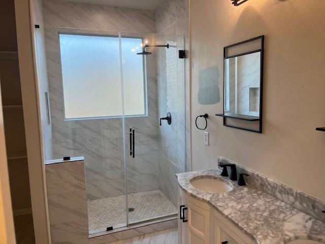 full bath with double vanity, a stall shower, plenty of natural light, and a sink