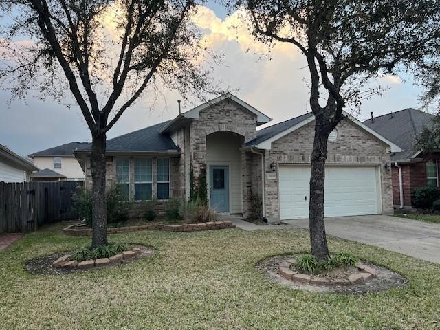 ranch-style home featuring brick siding, concrete driveway, an attached garage, fence, and a front lawn