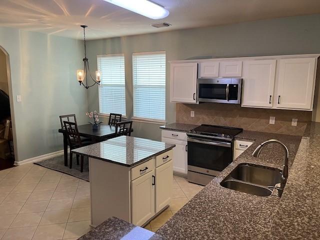 kitchen with stainless steel appliances, tasteful backsplash, white cabinets, light tile patterned flooring, and a sink