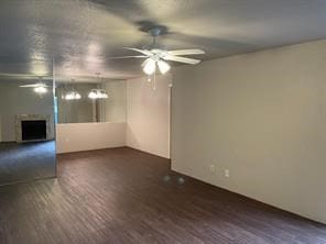 unfurnished room with a fireplace, a ceiling fan, and wood finished floors