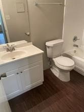 full bath with wood finished floors, shower / bath combination, vanity, and toilet