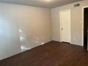 spare room with dark wood-type flooring and visible vents