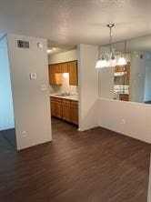 kitchen with dark wood-style flooring, visible vents, light countertops, brown cabinets, and pendant lighting