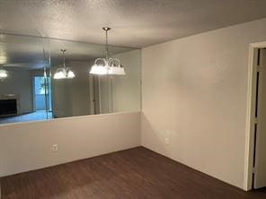 unfurnished dining area featuring dark wood-style floors and a textured ceiling