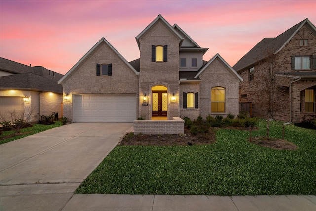 french country inspired facade with a garage, french doors, a lawn, and brick siding