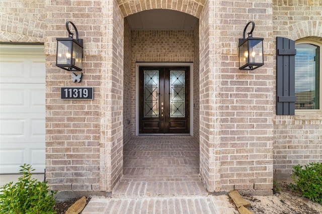 doorway to property featuring a garage and brick siding