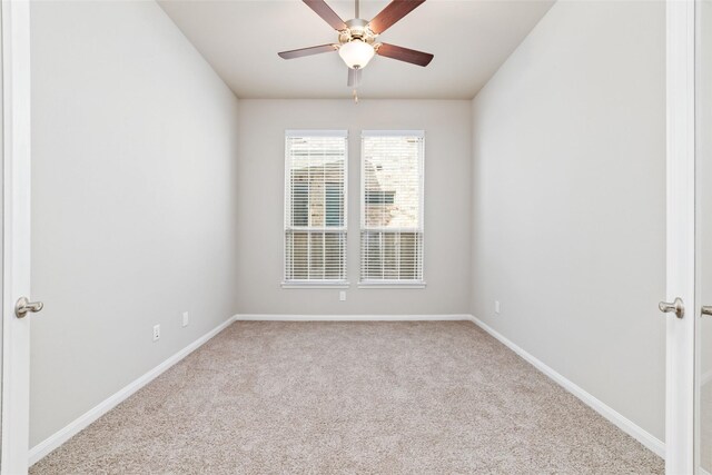 carpeted empty room featuring ceiling fan and baseboards