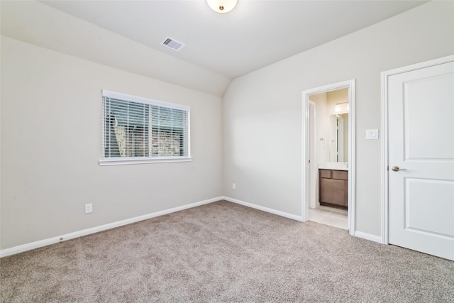 empty room with light carpet, baseboards, visible vents, and vaulted ceiling