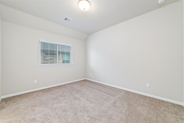 carpeted spare room with visible vents, vaulted ceiling, and baseboards