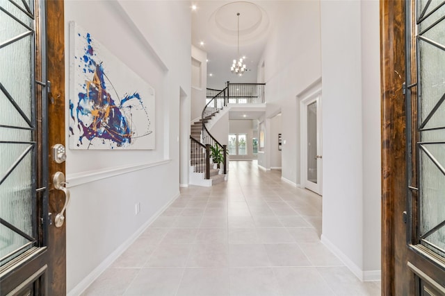 entryway featuring baseboards, stairway, tile patterned floors, a high ceiling, and a notable chandelier