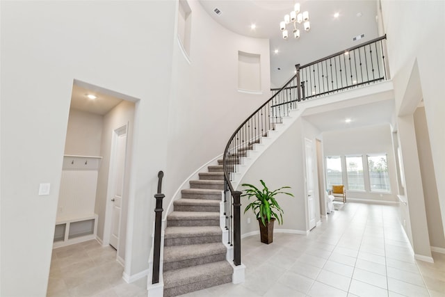 staircase with tile patterned flooring, a notable chandelier, recessed lighting, a towering ceiling, and baseboards