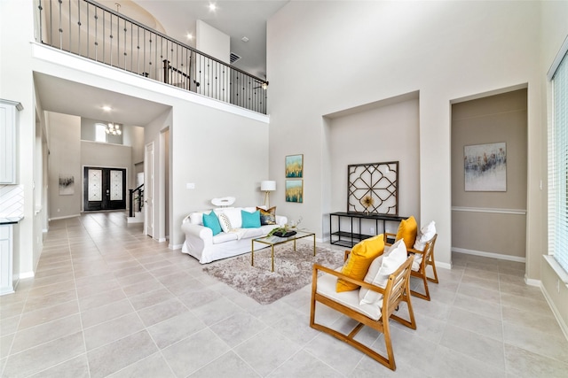 living room featuring light tile patterned flooring, a towering ceiling, and baseboards