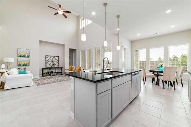 kitchen featuring light tile patterned floors, a wealth of natural light, dark countertops, open floor plan, and dishwasher