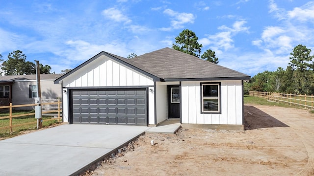 modern farmhouse style home with fence, board and batten siding, driveway, and roof with shingles