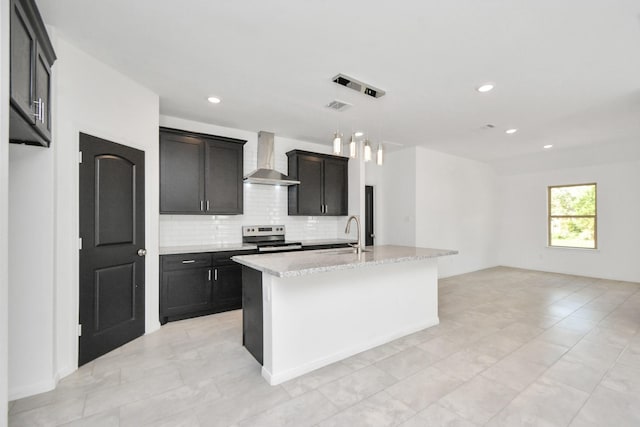 kitchen featuring stainless steel electric range oven, a kitchen island with sink, a sink, wall chimney exhaust hood, and backsplash