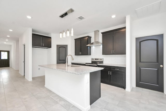 kitchen with visible vents, a sink, backsplash, wall chimney range hood, and stainless steel electric range oven