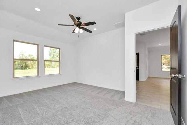 spare room with visible vents, vaulted ceiling, light carpet, recessed lighting, and a ceiling fan