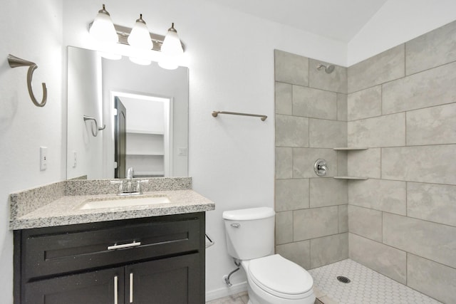 full bath with a tile shower, toilet, vanity, and baseboards